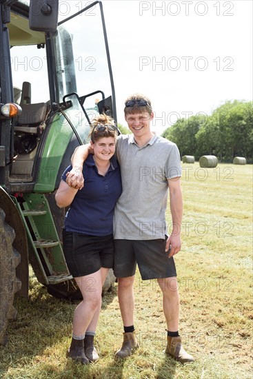 Smiling Caucasian couple posing near tractor