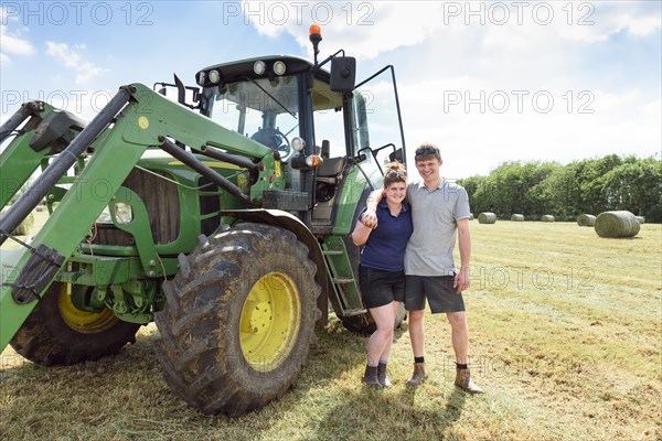 Smiling Caucasian couple posing near tractor