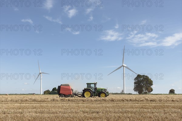 Caucasian man driving tractor near wind turbines