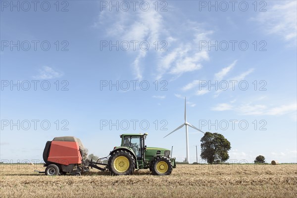 Caucasian man driving tractor near wind turbine
