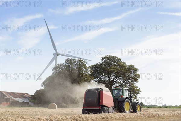 Caucasian man driving tractor near wind turbine