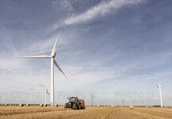 Caucasian man driving tractor near wind turbines