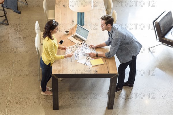 Caucasian man and woman examining photographs at table