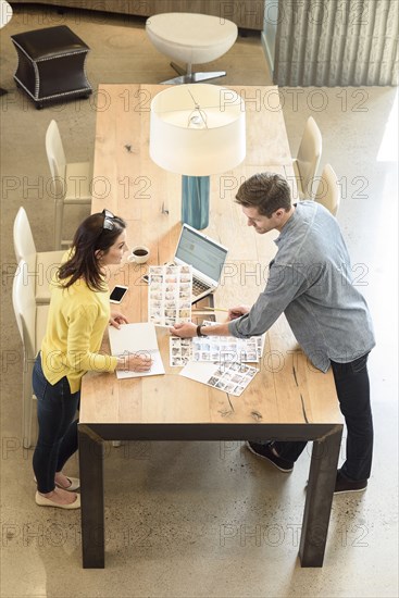 Caucasian man and woman examining photographs at table