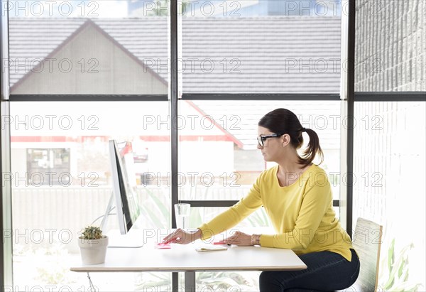 Caucasian woman writing on adhesive notes at desk