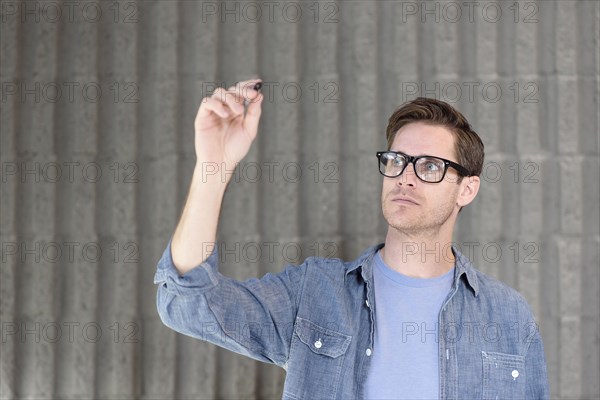 Caucasian man writing on glass wall