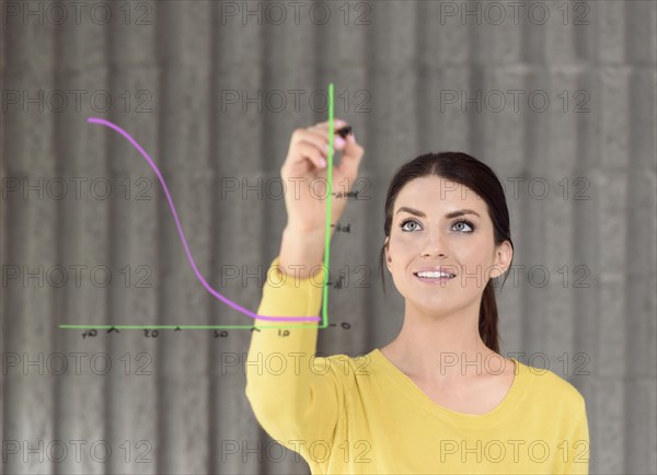 Caucasian woman drawing chart on glass wall