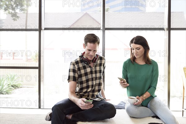Caucasian couple sitting on bench texting on cell phones