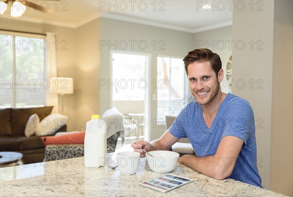 Portrait of smiling man eating bowl of cereal in morning