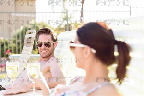 Caucasian couple relaxing in lounge chairs