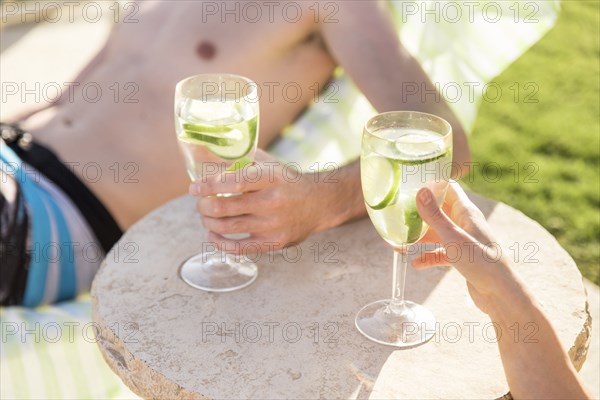 Caucasian couple relaxing in lounge chairs holding drinks