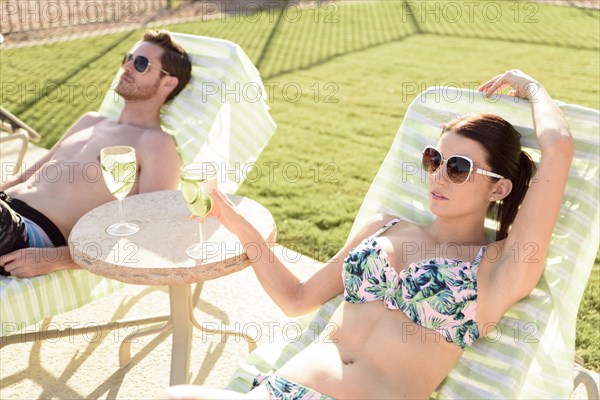 Caucasian couple relaxing in lounge chairs