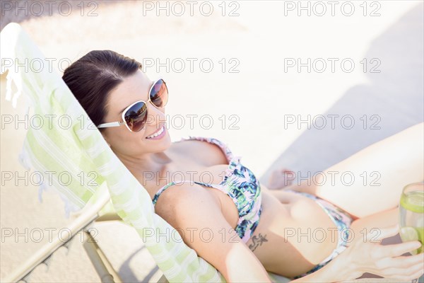 Caucasian woman relaxing in lounge chair holding drink