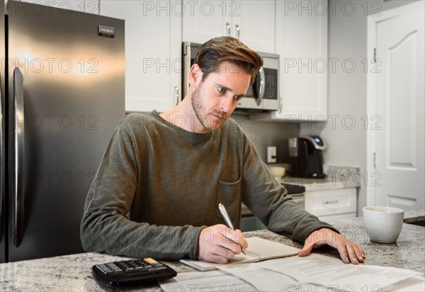 Serious Caucasian man writing notes and reading paperwork