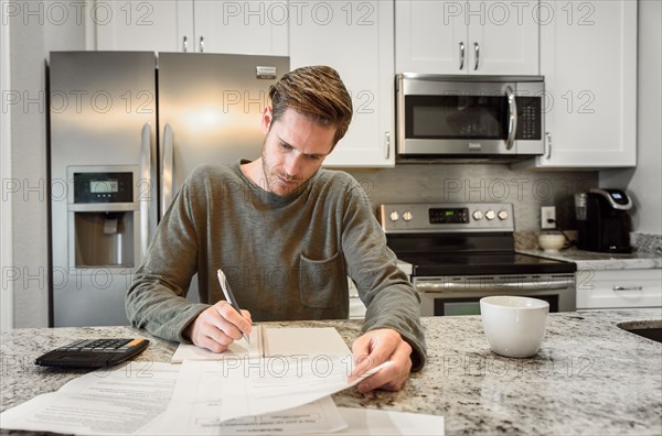 Serious Caucasian man writing notes and reading paperwork