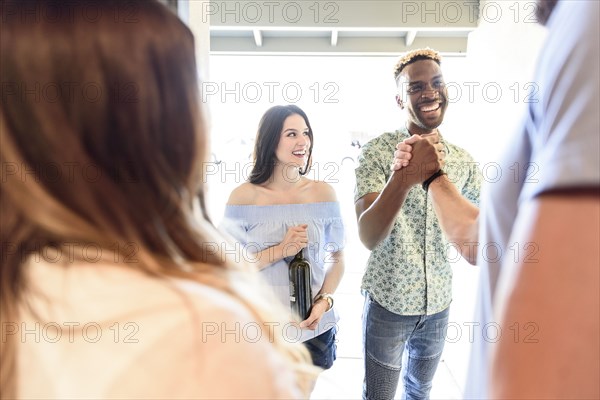 Man greeting friends in doorway