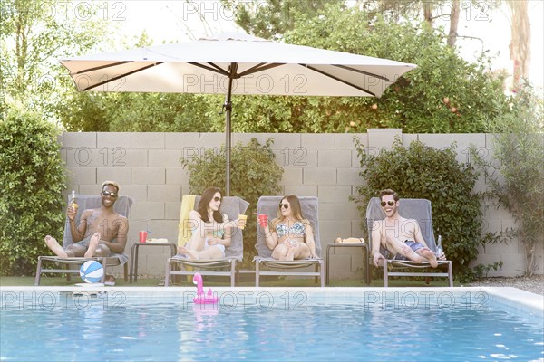 Friends relaxing with beer and cocktails at swimming pool