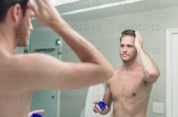 Caucasian main applying gel to hair