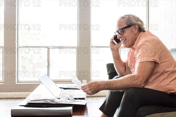 Smiling and Caucasian man sitting on sofa talking on cell phone