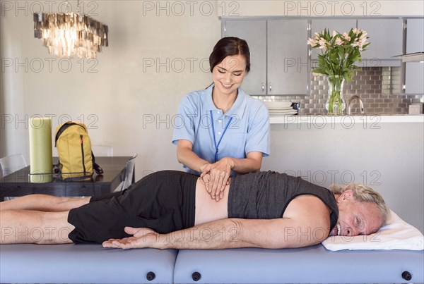 Physical therapist massaging back of man