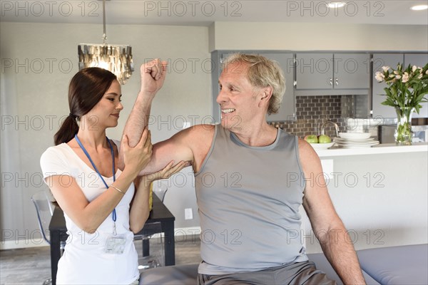 Physical therapist lifting arm of man