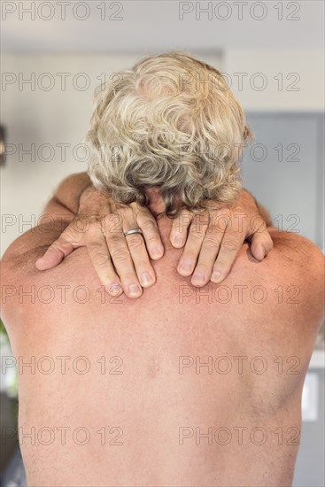 Hands of Caucasian man rubbing shoulders