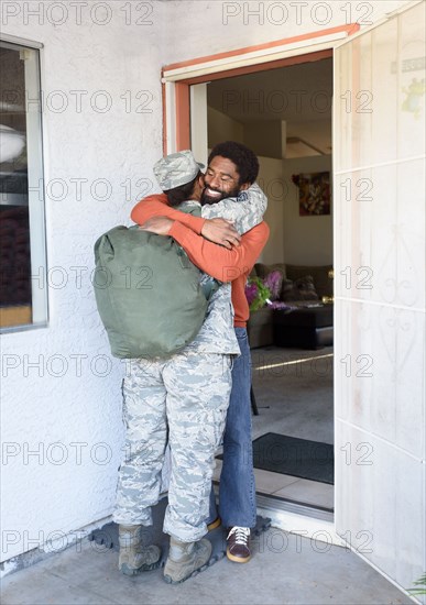 Black woman soldier hugging man in doorway