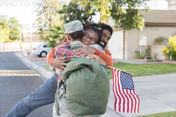 Black woman soldier hugging man and daughter