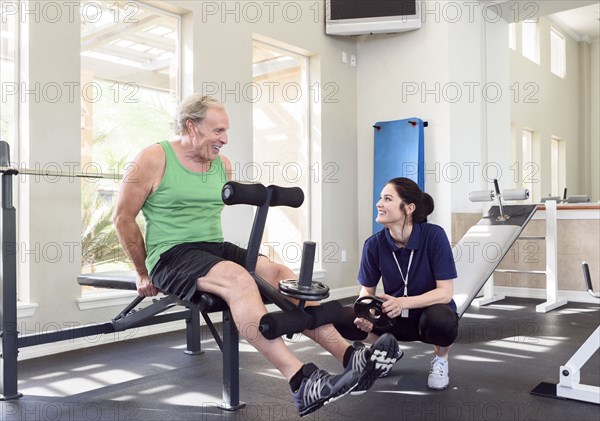 Caucasian trainer watching man strengthen legs