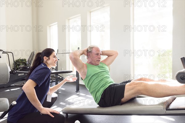 Caucasian trainer watching man doing sit-ups