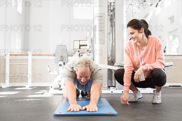 Caucasian trainer watching man stretching arms