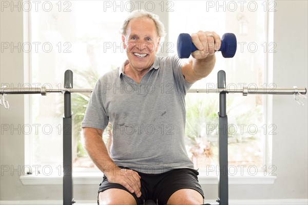 Caucasian man sitting on bench lifting dumbbell