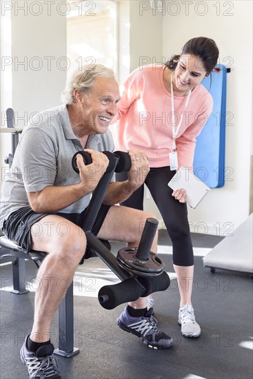 Caucasian trainer watching man strengthen arms