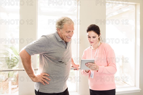 Caucasian trainer showing digital tablet to man