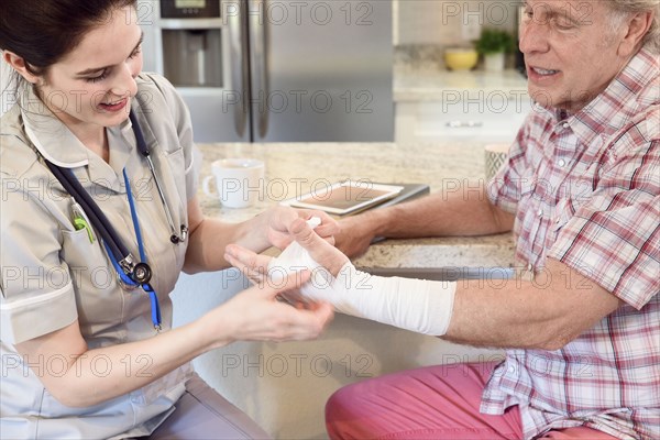 Caucasian nurse wrapping wrist of man