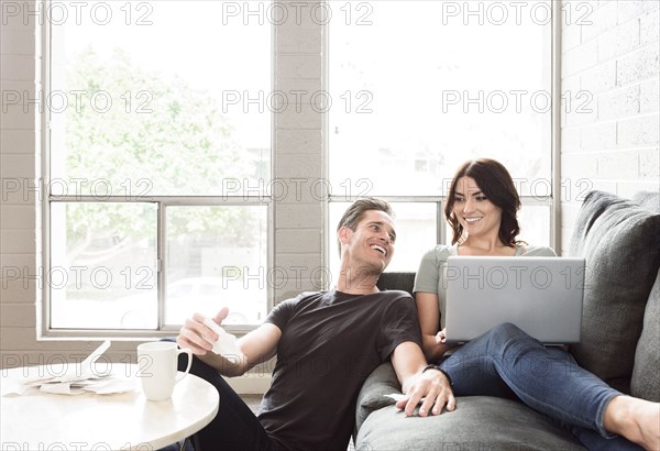 Caucasian couple using laptop on sofa