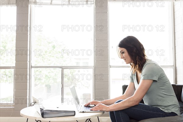 Caucasian woman using laptop on sofa