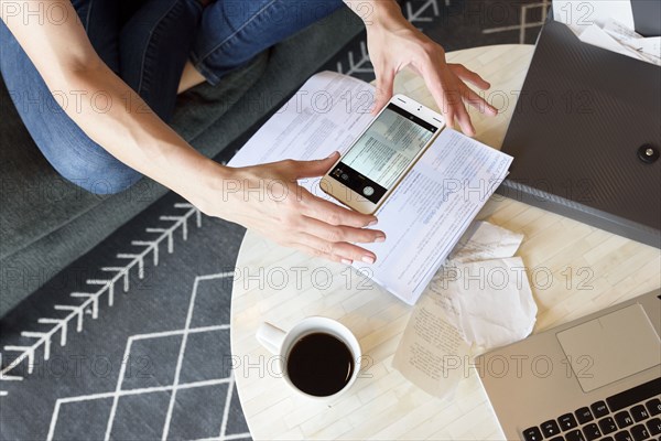 Caucasian woman photographing paperwork with cell phone