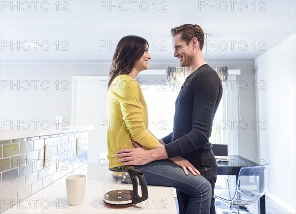Caucasian couple embracing on kitchen counter