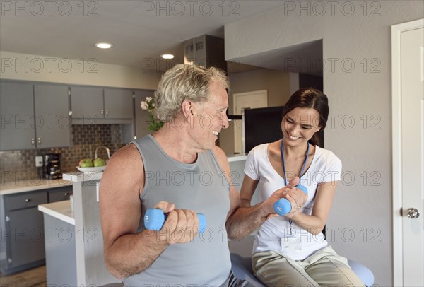 Physical therapist helping man lifting dumbbells