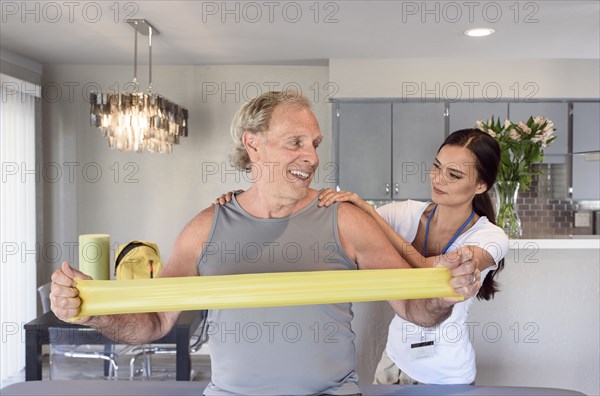 Physical therapist helping man using resistance band