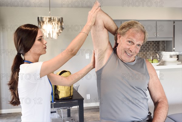 Physical therapist helping man stretch arm