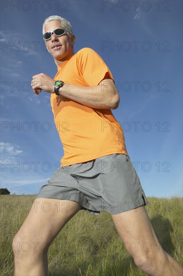 Middle-aged man running through grass in the countryside