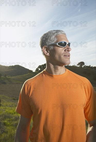 Middle-aged man standing in the sunlight in the countryside