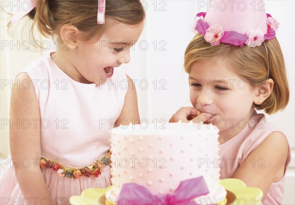 Young girls picking at a birthday cake