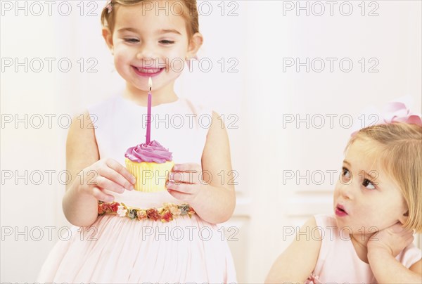 Young girl holding a birthday cupcake