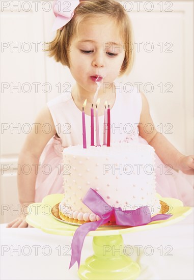 Young girl blowing out the candles on a birthday cake