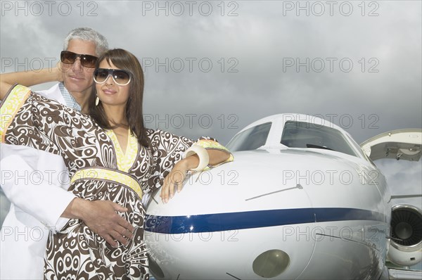 Couple hugging and leaning on the nose of a small jet