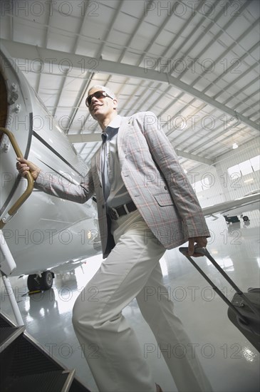 Middle-aged man boarding airplane in hanger