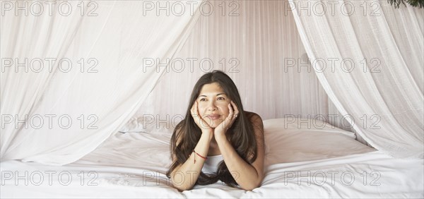 Young woman relaxing in a four-poster bed